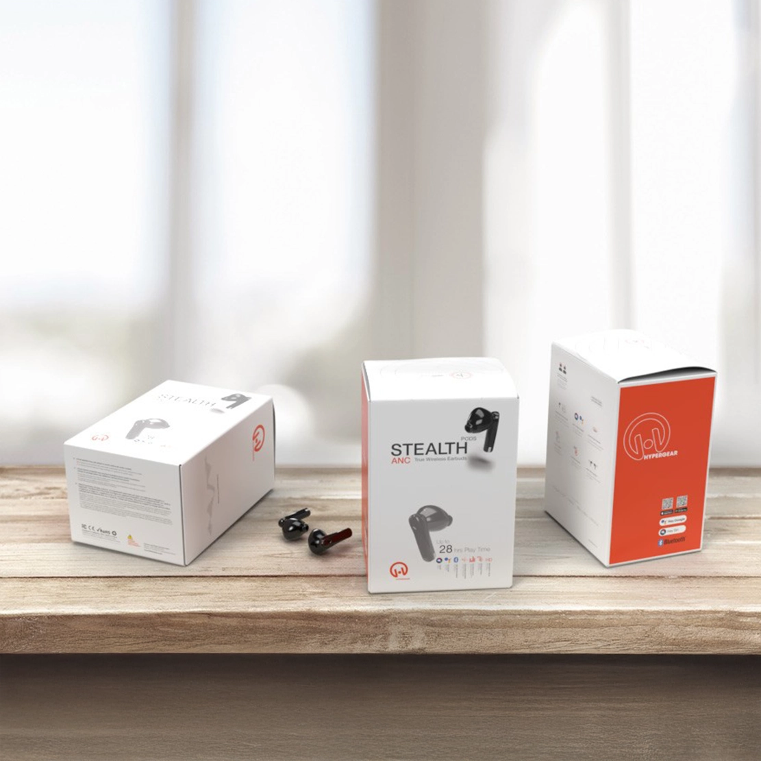 A product display showcasing the packaging for HyperGear’s Stealth ANC earbuds on a wooden surface. Three boxes are featured: one lying on its side displaying detailed product information, one standing upright with the front-facing design showing the product name ‘Stealth ANC’ and an image of the earbuds, and the third showing the side panel with a bold orange background and the HyperGear logo, QR code, and other product details. Two earbuds are placed loosely on the table in front of the boxes, emphasizing the product’s sleek, modern design.