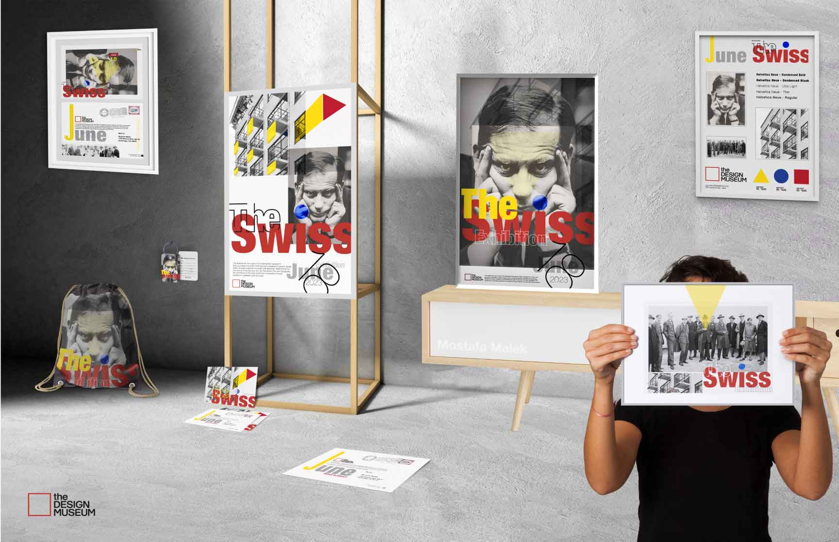 A comprehensive visual showcase of ‘The Swiss’ design project displayed in a minimalist exhibition setting. The display includes posters, prints, a tote bag, and other branded materials, featuring bold Swiss-style design elements such as geometric shapes, modern typography, and a grayscale portrait. Vibrant yellow, red, and blue accents highlight the designs, emphasizing the clean and structured aesthetic of Swiss minimalism.