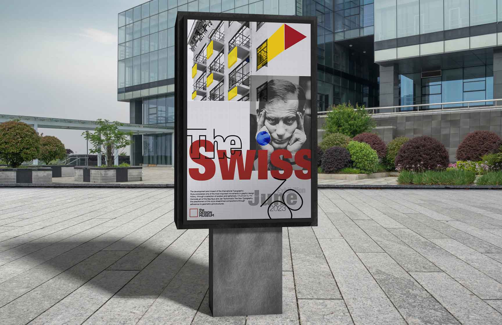 An outdoor advertisement display showcasing ‘The Swiss’ exhibition poster. The design features a grayscale portrait of a thoughtful man, geometric shapes in yellow, red, and blue, and bold red typography. The background highlights Bauhaus-style architecture with balconies. The modern composition emphasizes clean lines, structured aesthetics, and typographic precision. The poster is situated in a modern plaza with contemporary glass buildings and landscaped greenery in the background.