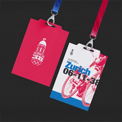 Event passes for the Zurich 2038 Winter Olympic Games, featuring a vibrant Swiss-style design. One pass showcases the Zurich Olympic logo on a red background, while the other highlights cycling imagery, event details, and blue accents, both attached to red and blue lanyards against a black background.